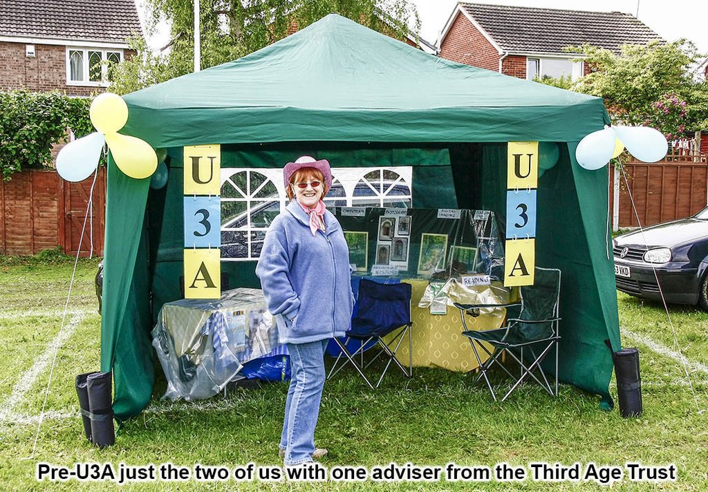 smiling lady standing by a gazebo advertising u3a